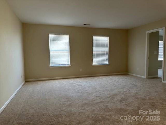 spare room featuring baseboards, visible vents, and light colored carpet