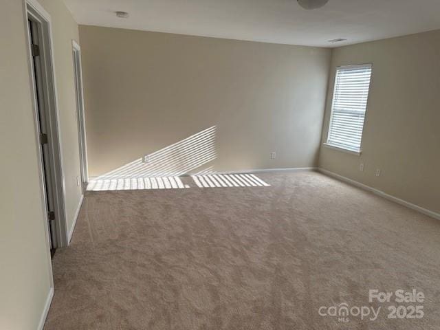 carpeted spare room featuring baseboards