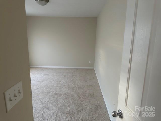 empty room featuring baseboards and light colored carpet