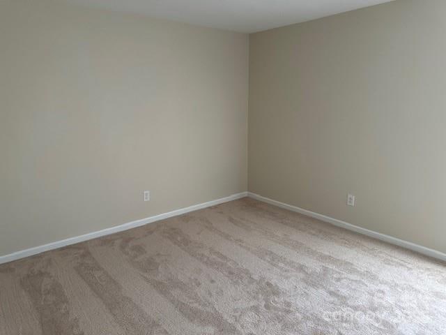 empty room featuring light carpet and baseboards