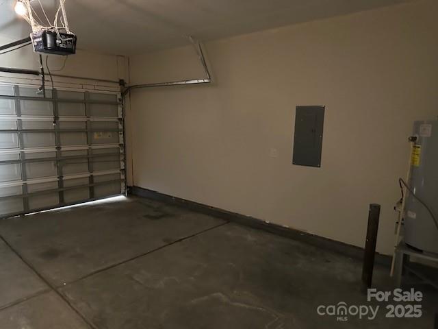 garage featuring baseboards, gas water heater, electric panel, and a garage door opener