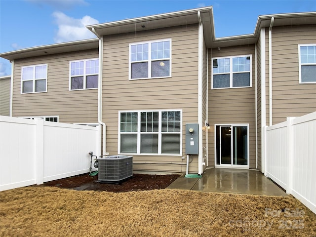 rear view of house with a yard, fence, and central AC unit