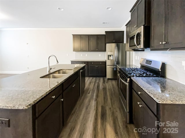 kitchen with appliances with stainless steel finishes, dark wood-type flooring, a sink, and light stone countertops