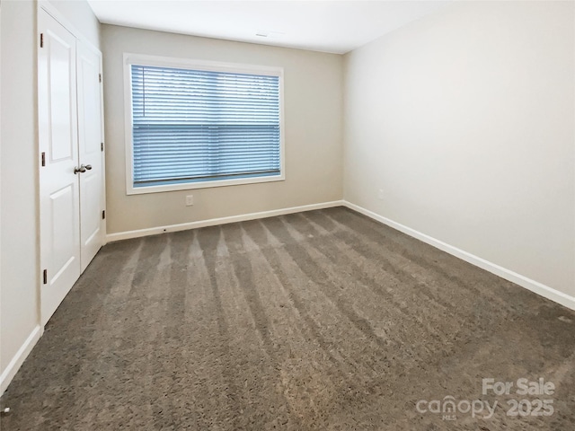 empty room featuring carpet and baseboards