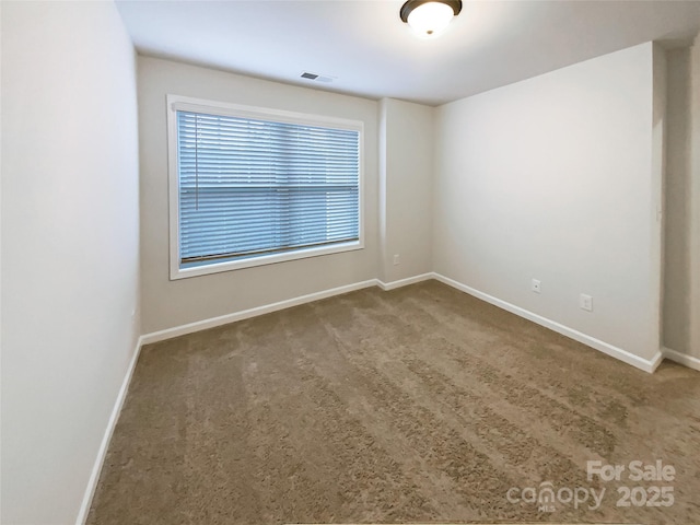 spare room featuring carpet, visible vents, and baseboards