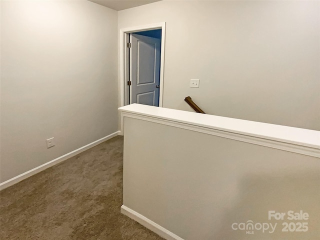 corridor featuring dark carpet and baseboards