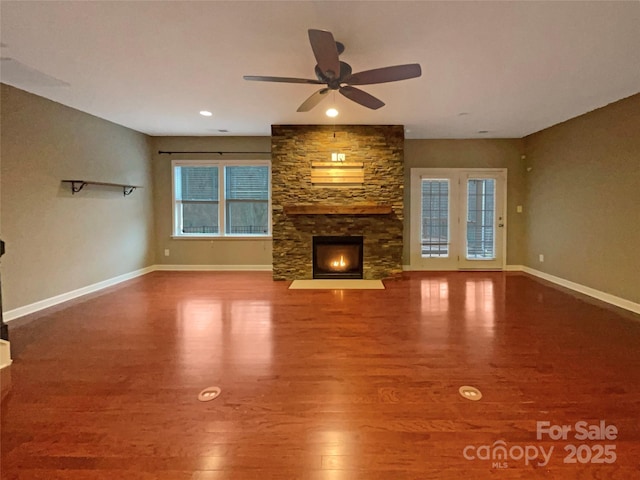 unfurnished living room with a fireplace, wood finished floors, a ceiling fan, and baseboards