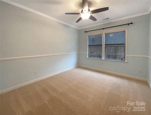 carpeted spare room featuring a ceiling fan, visible vents, crown molding, and baseboards