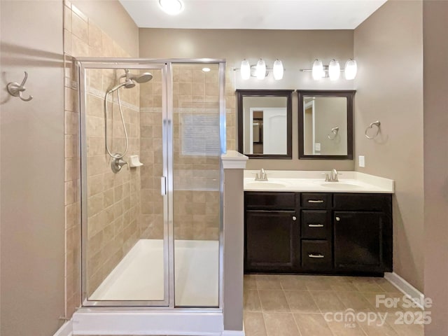 full bath with a sink, double vanity, tile patterned flooring, and a shower stall