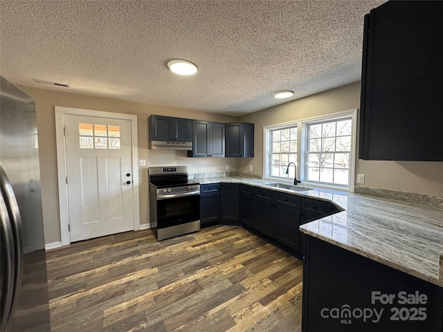 kitchen with light stone counters, stainless steel appliances, a sink, wood finished floors, and under cabinet range hood