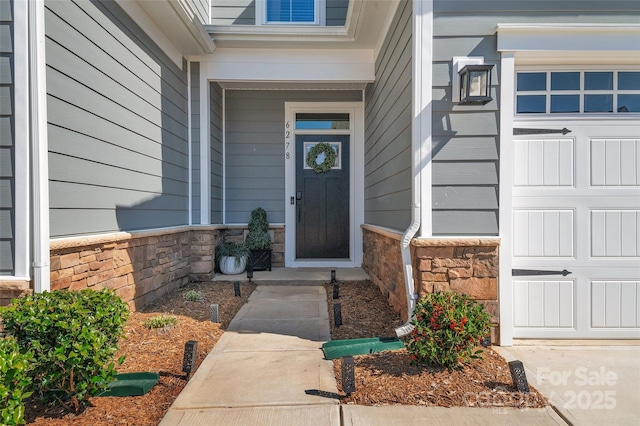 property entrance with a garage and stone siding