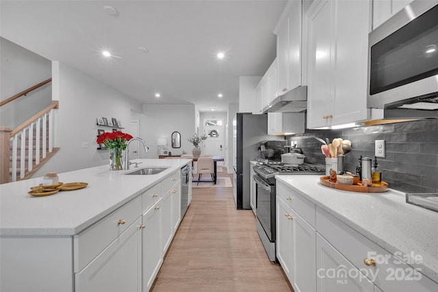 kitchen featuring appliances with stainless steel finishes, a sink, white cabinetry, and under cabinet range hood