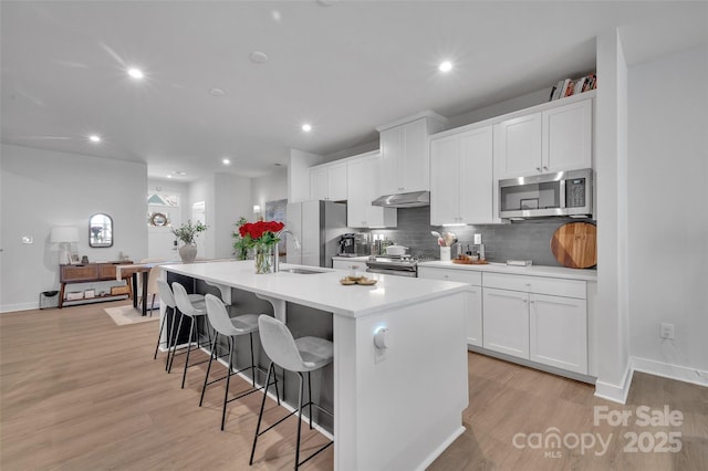 kitchen featuring white cabinets, a kitchen island with sink, appliances with stainless steel finishes, and light countertops