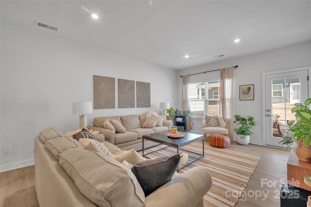 living room with light wood-type flooring, visible vents, baseboards, and recessed lighting