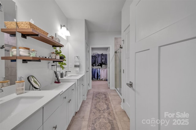 bathroom with a spacious closet, a shower stall, vanity, and tile patterned floors