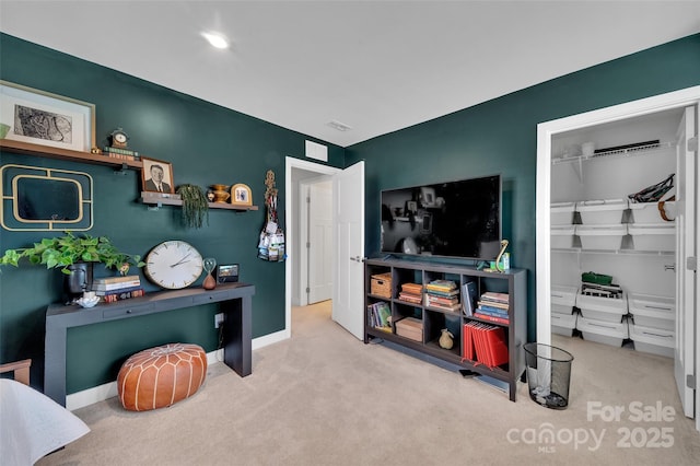 bedroom with a closet, light colored carpet, a spacious closet, and baseboards