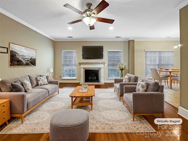 living area with crown molding, wood finished floors, and a fireplace with flush hearth