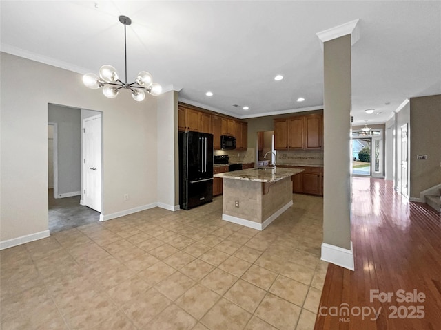 kitchen featuring decorative backsplash, an island with sink, ornamental molding, black appliances, and a chandelier