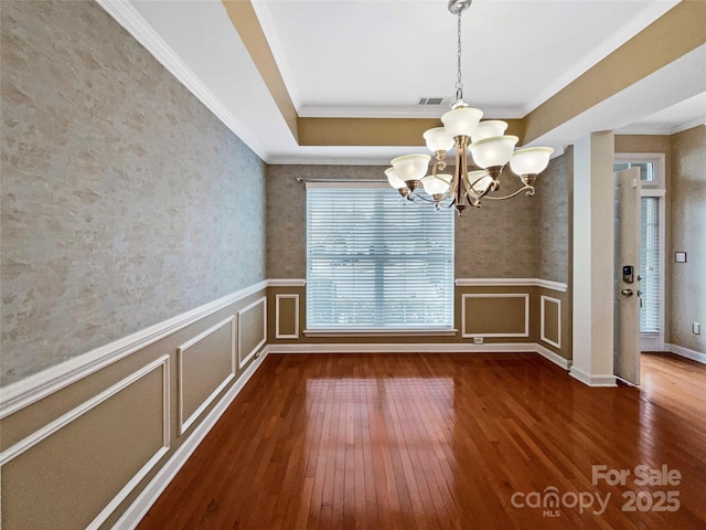 unfurnished dining area with visible vents, a wainscoted wall, a chandelier, and hardwood / wood-style flooring