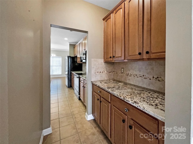 kitchen featuring light tile patterned floors, electric range, tasteful backsplash, stainless steel microwave, and light stone countertops