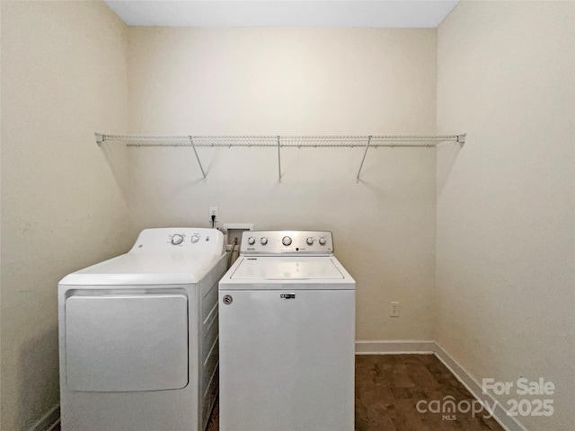 laundry area with laundry area, dark wood-style flooring, washing machine and clothes dryer, and baseboards