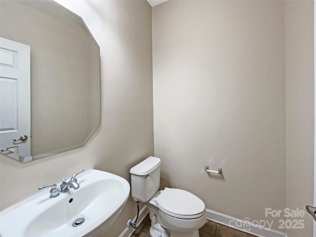 bathroom featuring baseboards, a sink, and toilet