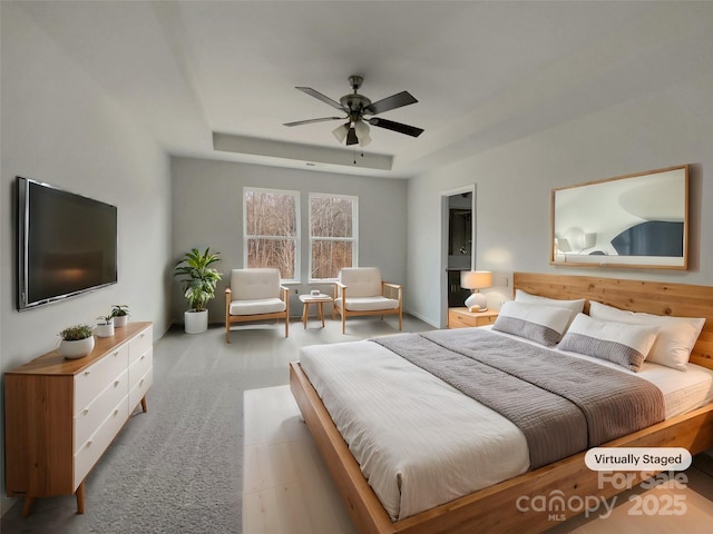 bedroom featuring light carpet, ceiling fan, and a tray ceiling