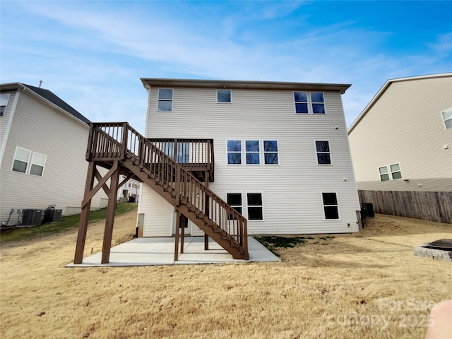 rear view of property with a lawn, a patio, stairs, fence, and central air condition unit