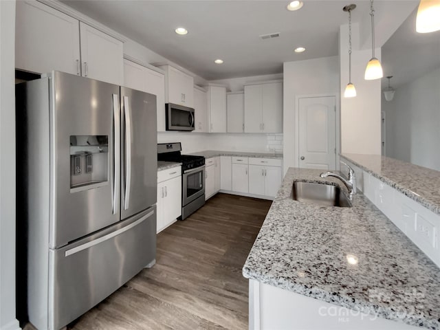 kitchen featuring white cabinetry, stainless steel appliances, light stone counters, and pendant lighting