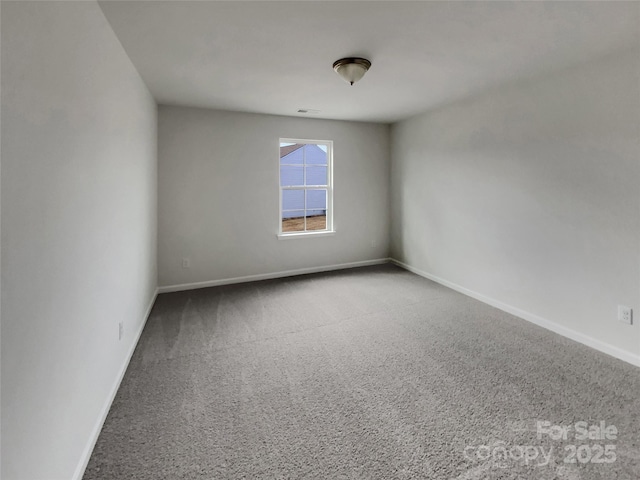 empty room featuring carpet floors, visible vents, and baseboards