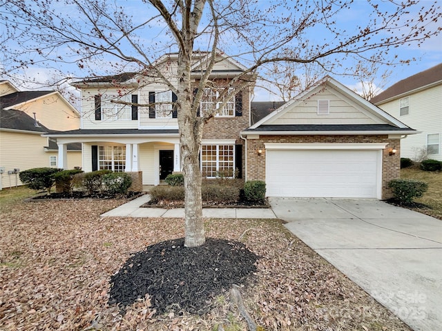 traditional home with a garage, concrete driveway, brick siding, and a balcony