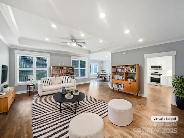 living room featuring ornamental molding, a tray ceiling, and light wood finished floors