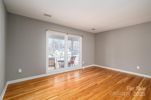 spare room with visible vents, light wood-style flooring, and baseboards