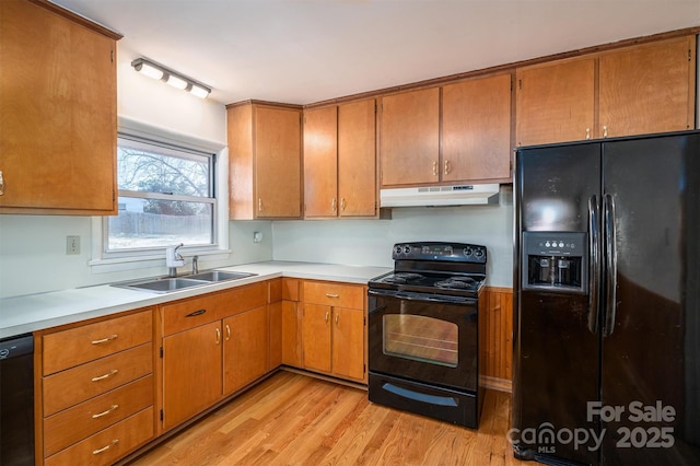 kitchen with under cabinet range hood, a sink, light countertops, brown cabinets, and black appliances