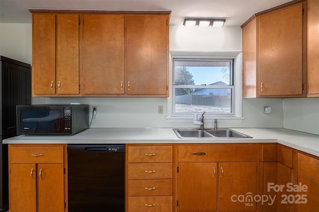 kitchen featuring brown cabinetry, light countertops, a sink, and black appliances