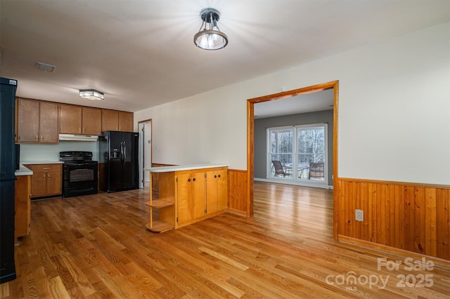 kitchen with brown cabinets, a peninsula, light countertops, black appliances, and open shelves