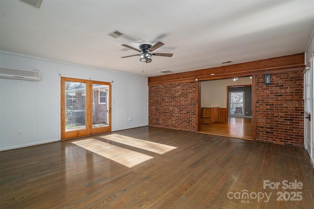 interior space featuring brick wall, visible vents, dark wood-style flooring, and a wall mounted air conditioner