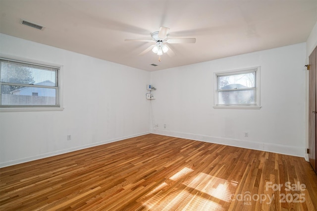 spare room featuring a ceiling fan, wood finished floors, visible vents, and baseboards