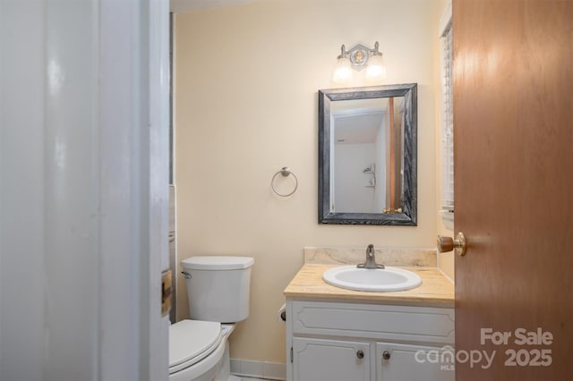 bathroom featuring baseboards, vanity, and toilet