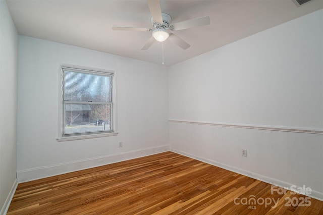 empty room featuring wood finished floors, a ceiling fan, and baseboards