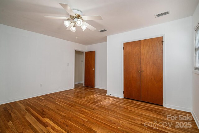 unfurnished bedroom featuring a closet, wood finished floors, visible vents, and baseboards