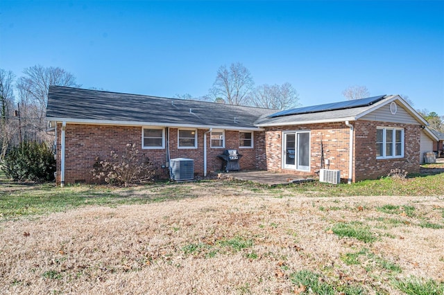 rear view of property with a patio area, solar panels, brick siding, and central air condition unit