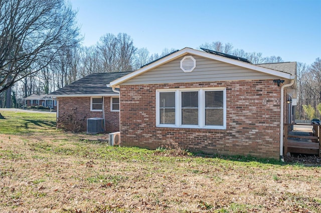 rear view of property featuring a yard, brick siding, and central air condition unit