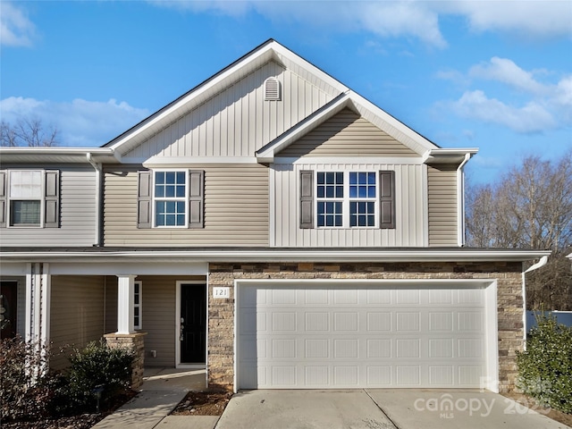 view of front of home with board and batten siding, stone siding, an attached garage, and concrete driveway