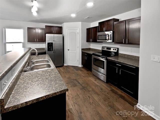 kitchen featuring stainless steel appliances, dark wood finished floors, a sink, and dark brown cabinets