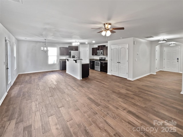 kitchen featuring appliances with stainless steel finishes, open floor plan, dark wood finished floors, and ceiling fan with notable chandelier