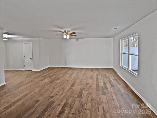 spare room with dark wood-style floors, visible vents, and baseboards