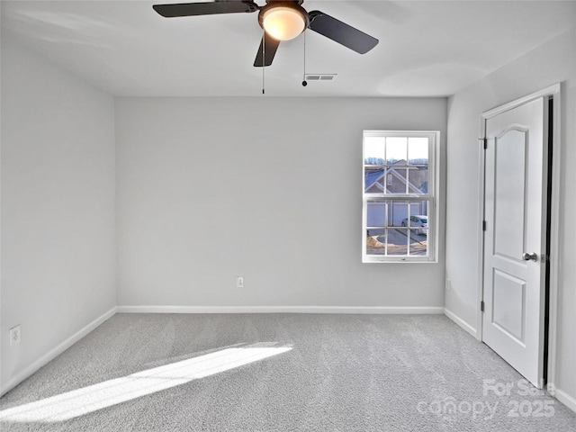 carpeted empty room featuring a ceiling fan, visible vents, and baseboards