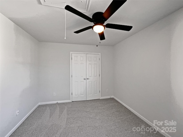 unfurnished bedroom with attic access, baseboards, ceiling fan, carpet, and a closet