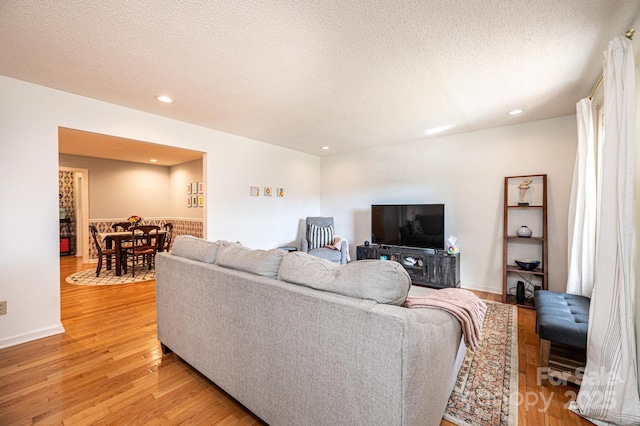 living room featuring recessed lighting, light wood-style flooring, and a textured ceiling